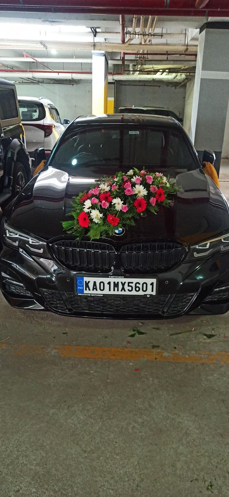 Black BMW wedding car with a red rose bouquet