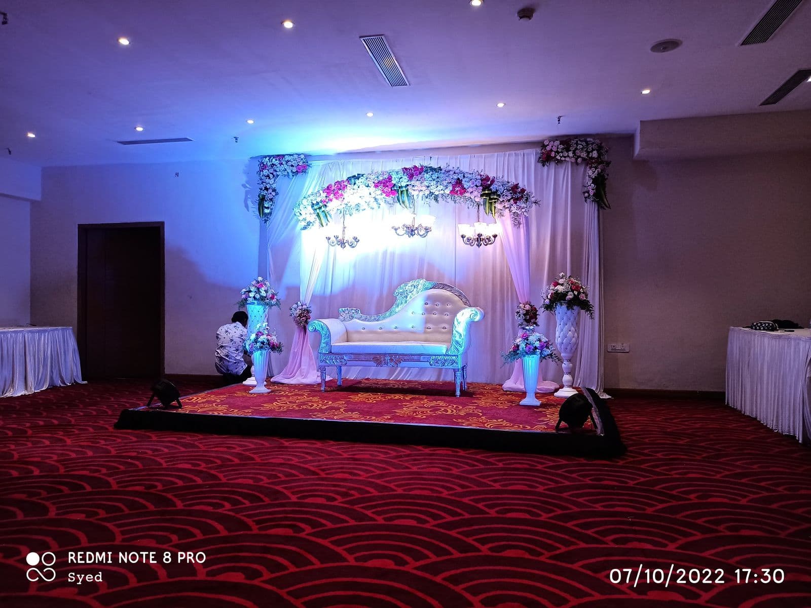 Floral stage with white chaise under blue lighting