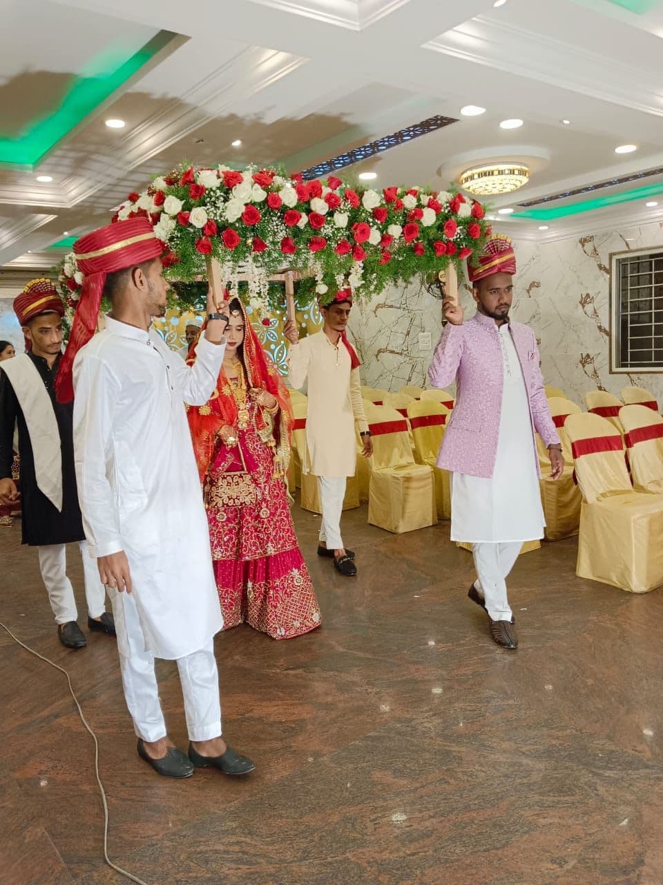 Bride entering under a phoolon ki chadar held by her family