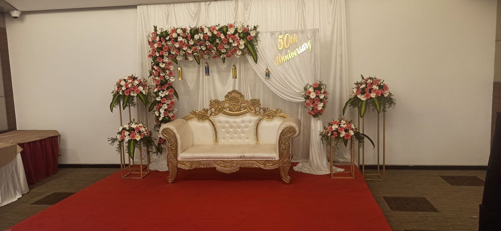 Gold sofa stage with pink florals and red carpet
