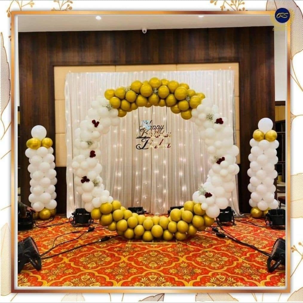 Gold and white balloon ring with balloon pillars on a hall stage