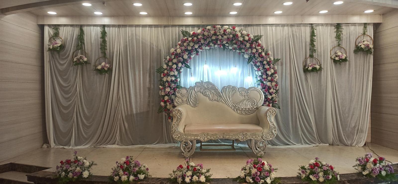Grey drape stage with white floral ring and sofa