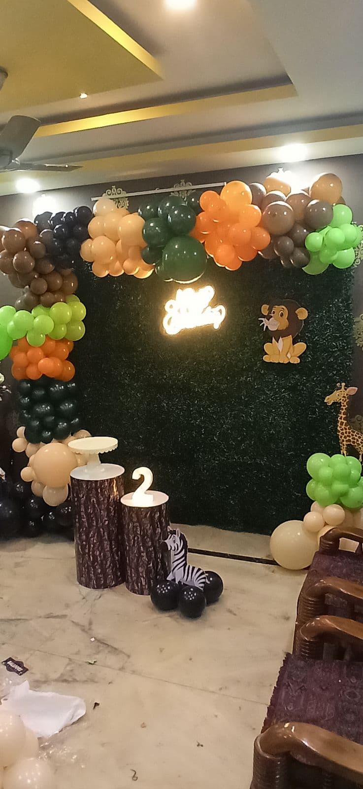 Jungle-themed birthday backdrop with green grass wall, animal props and balloons