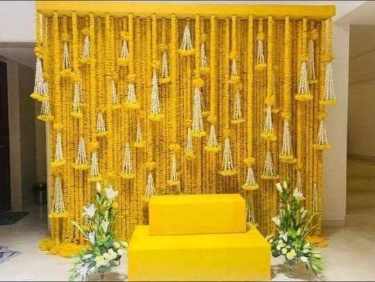 Marigold string wall with a yellow bride seat for haldi
