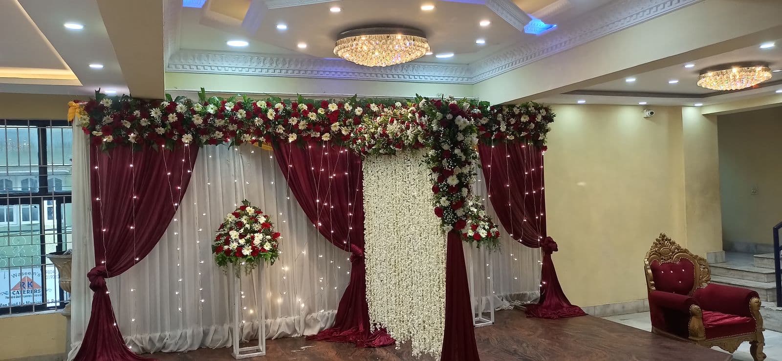 Maroon and white drape stage with rose canopy for the couple