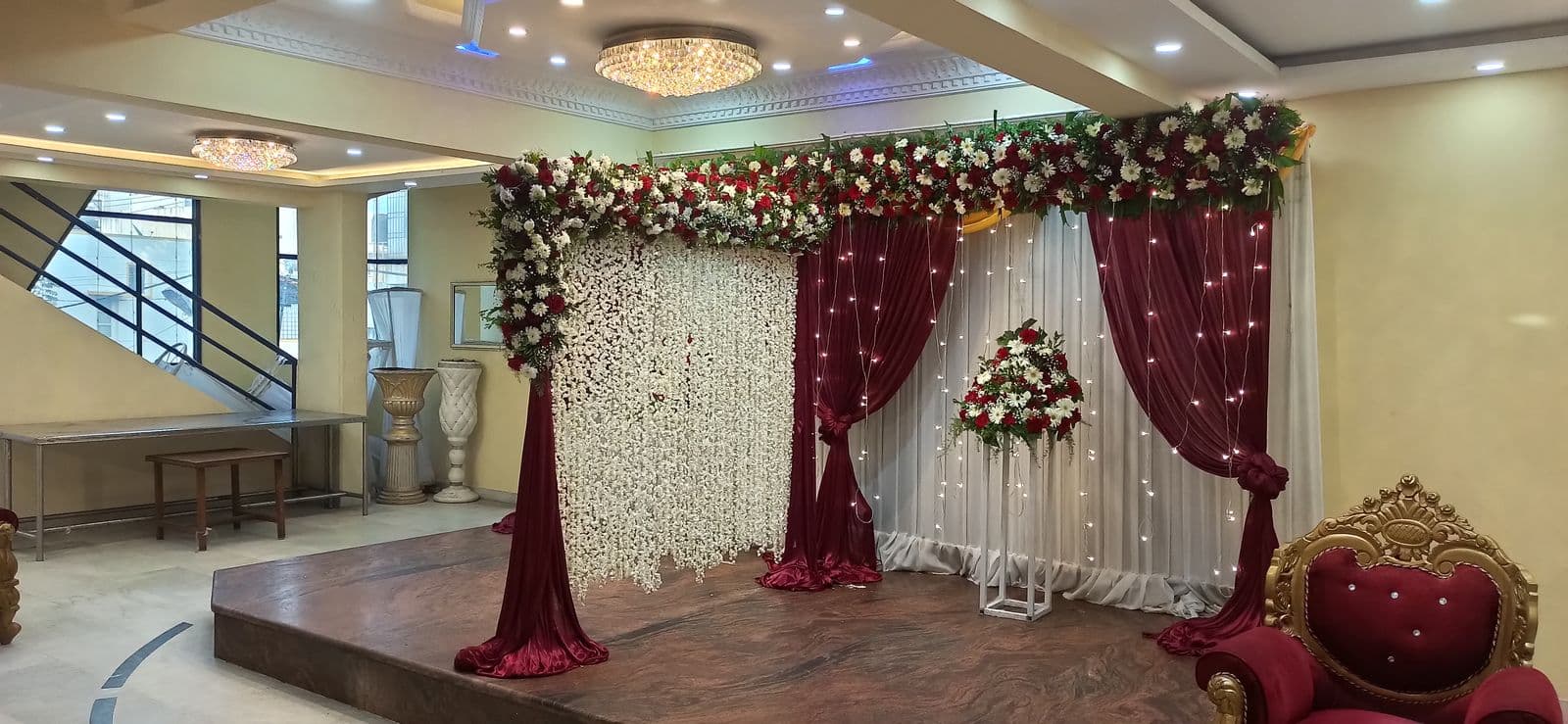 Wide view of a maroon and white floral wedding stage