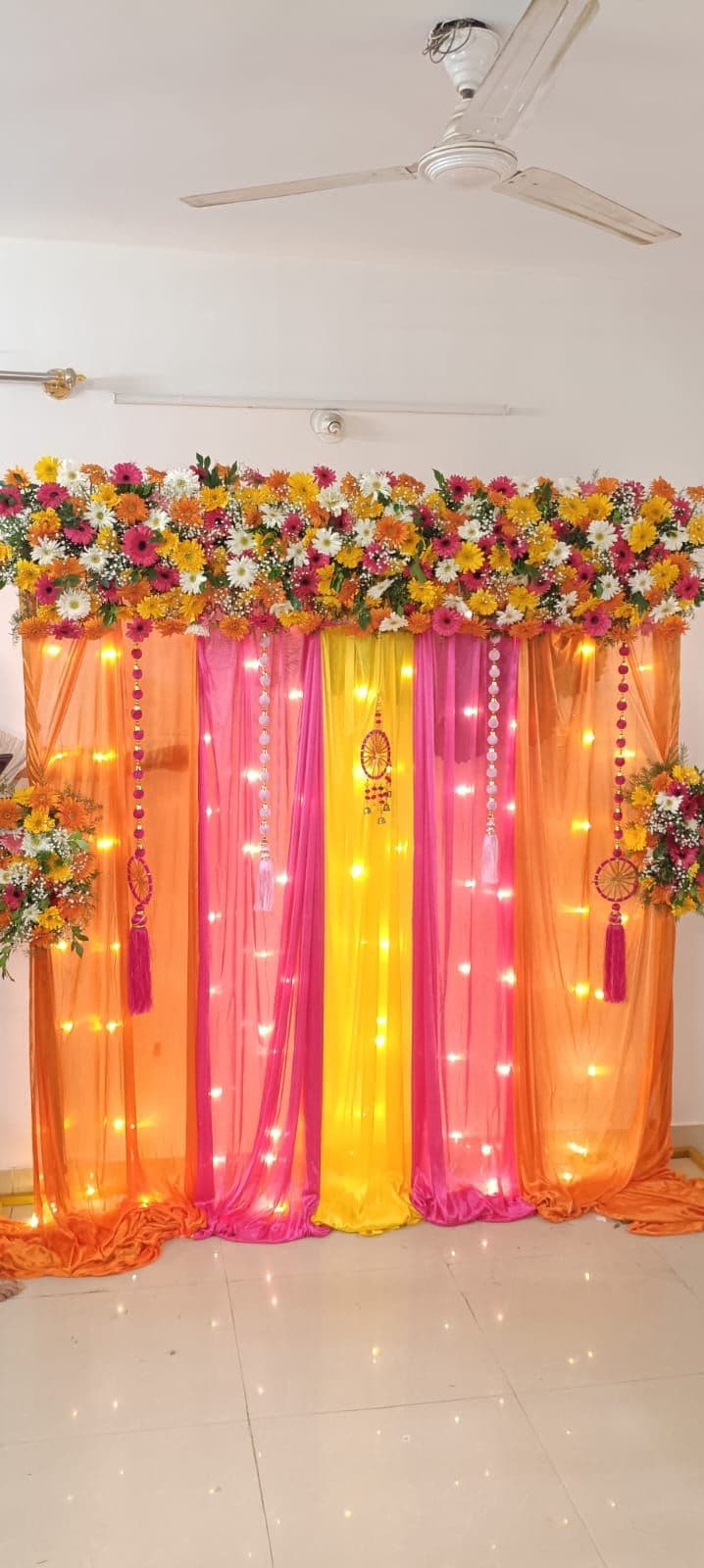 Orange, pink and yellow drape mehendi backdrop with fairy lights