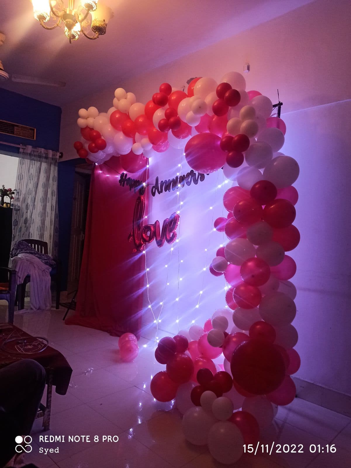 Pink and red balloon wall with anniversary neon