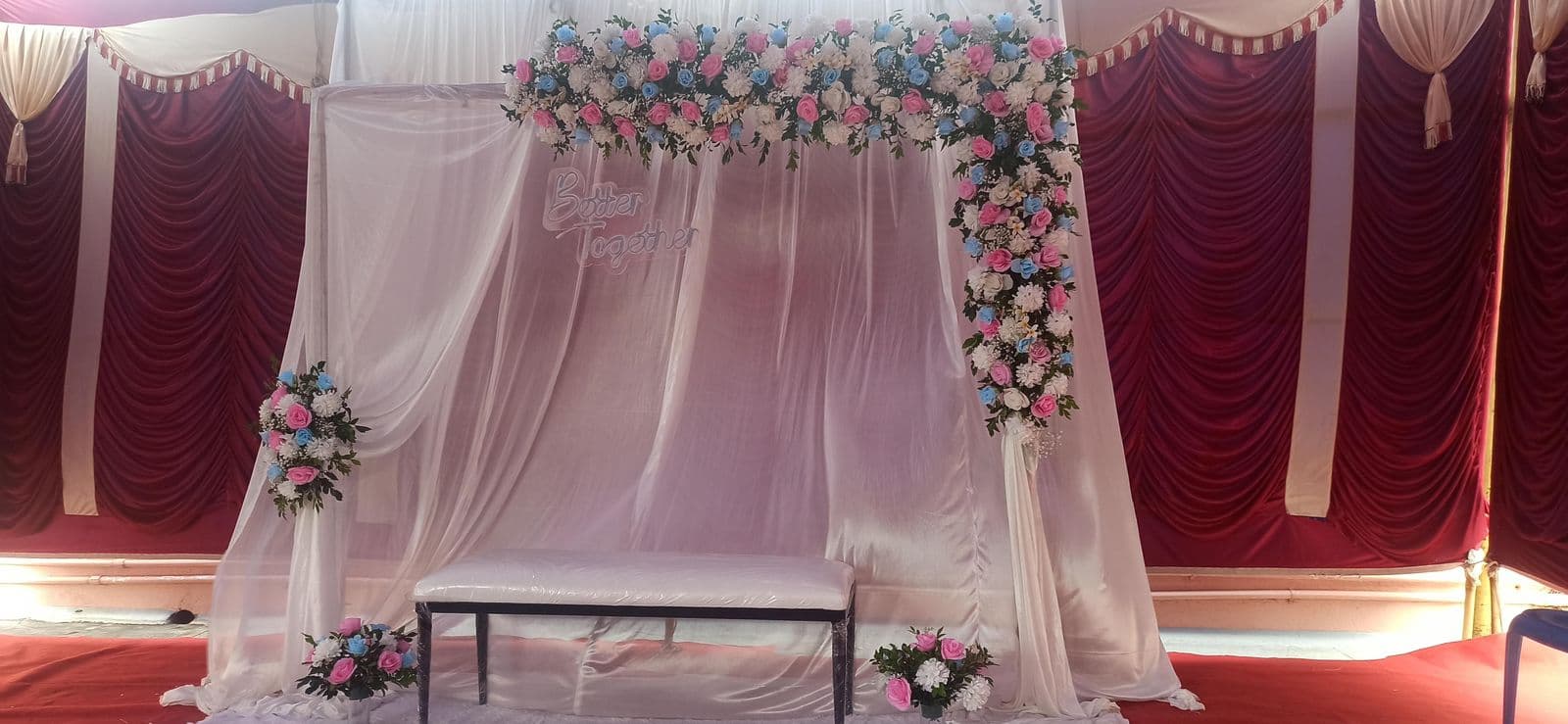 Pink drape backdrop with rose corners and maroon swags
