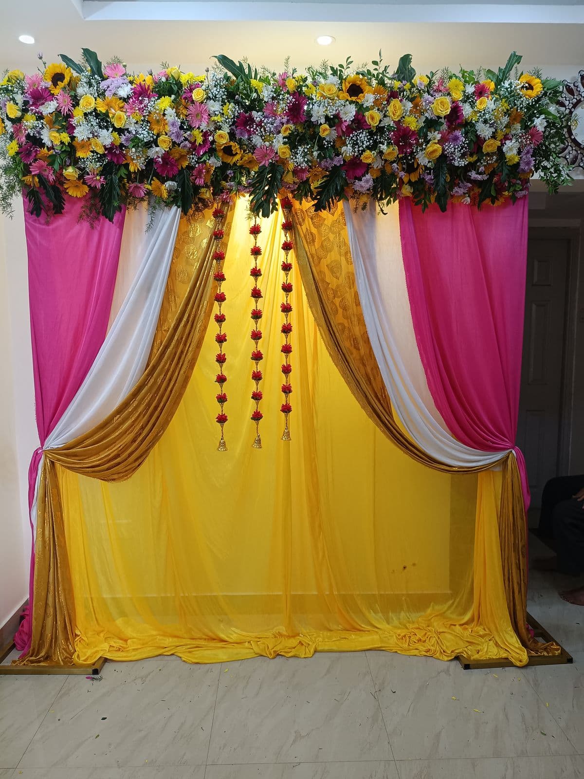 Pink and yellow drape haldi backdrop with mixed flower top