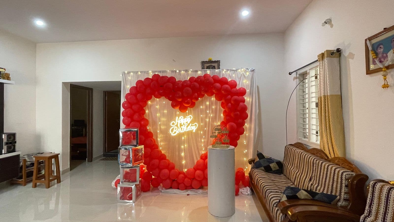 Red heart balloon backdrop set up in a living room for a surprise birthday