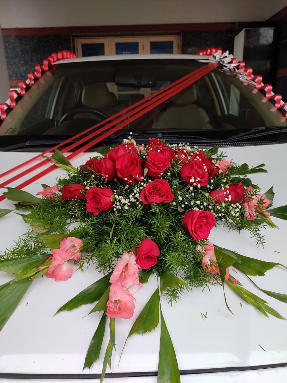 Close-up of a red rose and gladioli bouquet on a wedding car bonnet