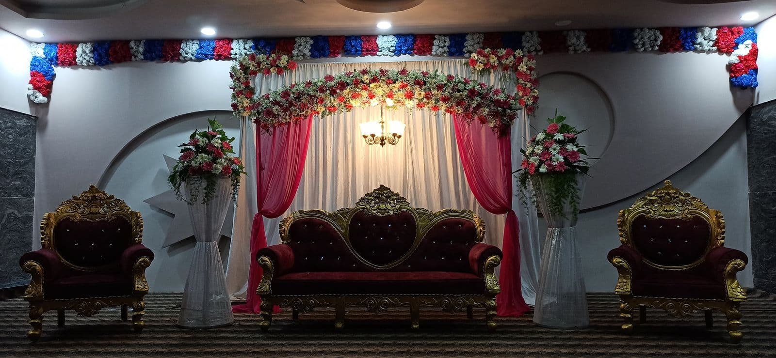 Red and white drape stage with maroon sofas