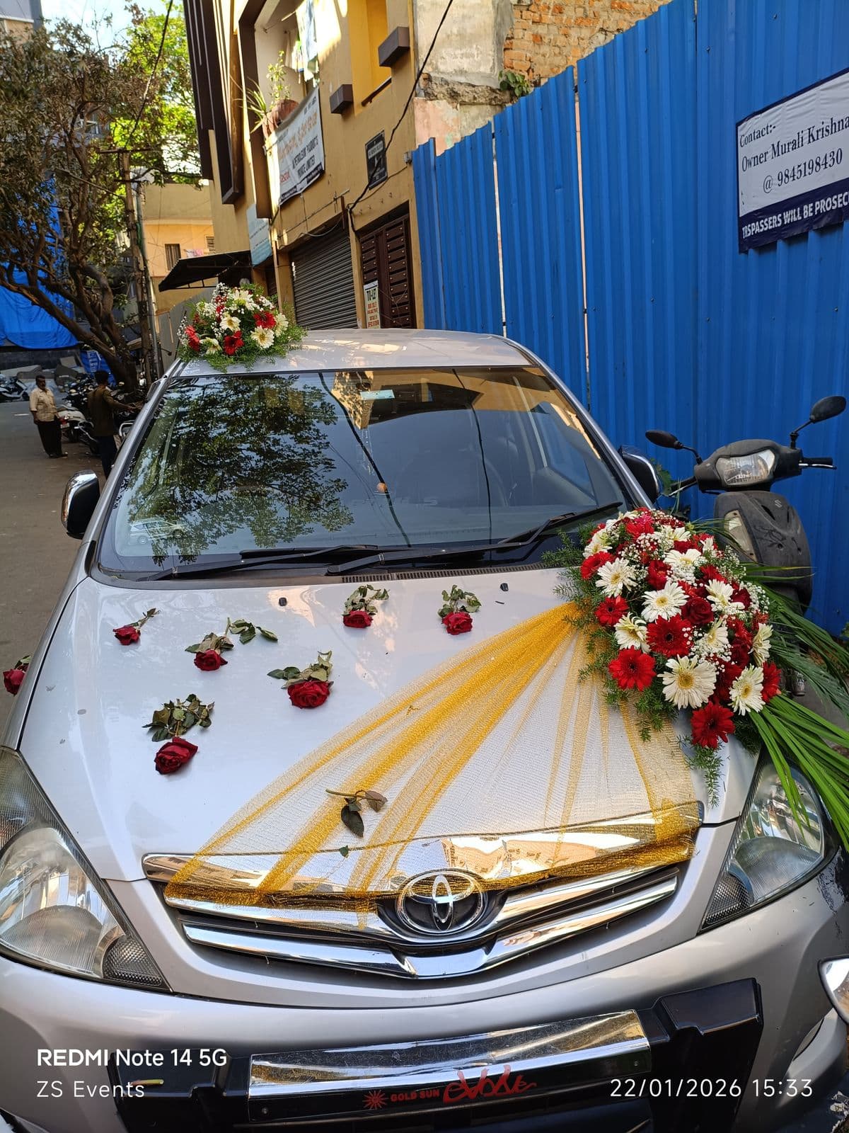 Silver Innova wedding car with yellow ribbons and red rose bouquet