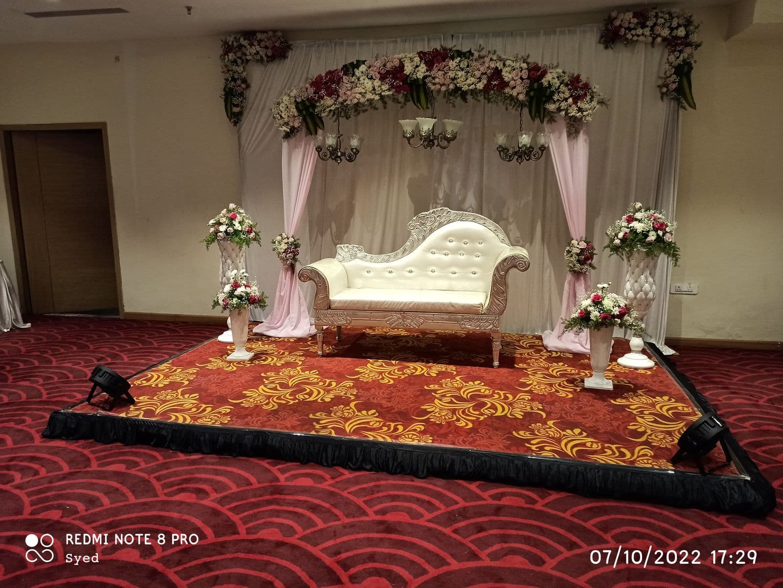 White chaise under a rose canopy on a hall stage