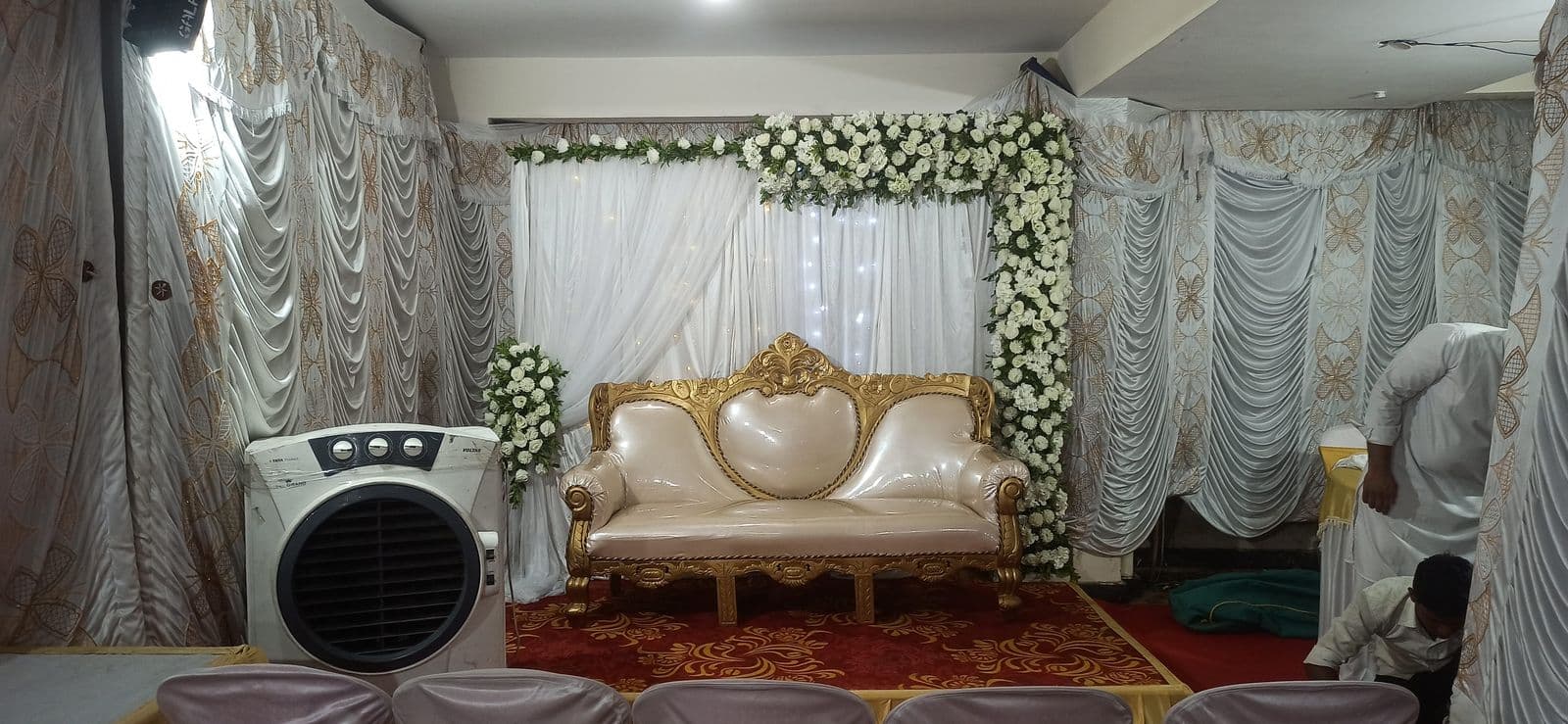 Small white drape stage with gold chaise and florals