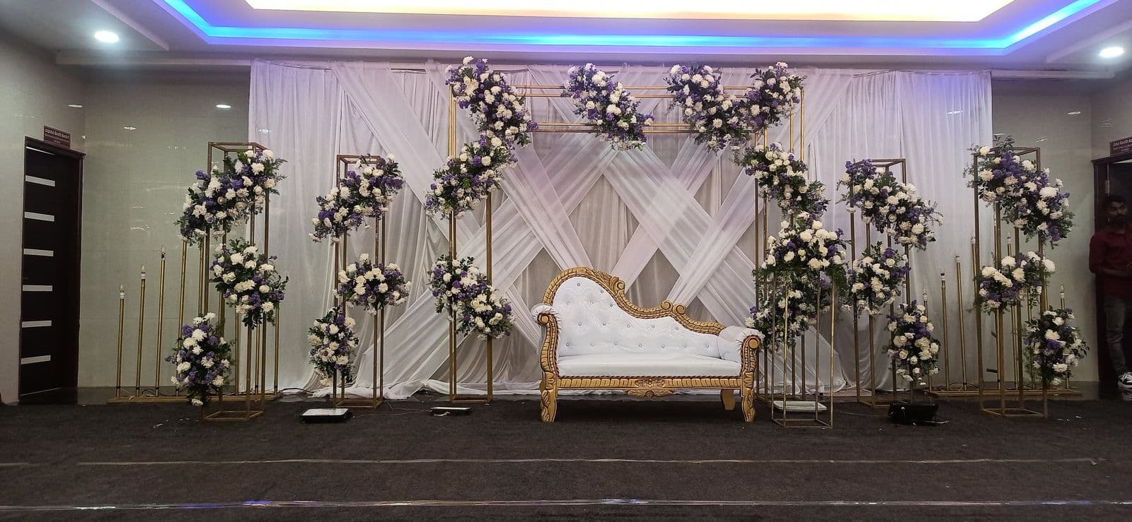Wide white wedding stage with floral stands and lighting