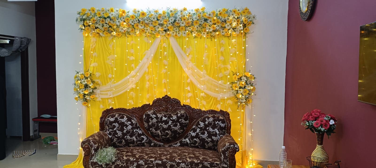 Yellow drape mehendi backdrop with floral top and sofa