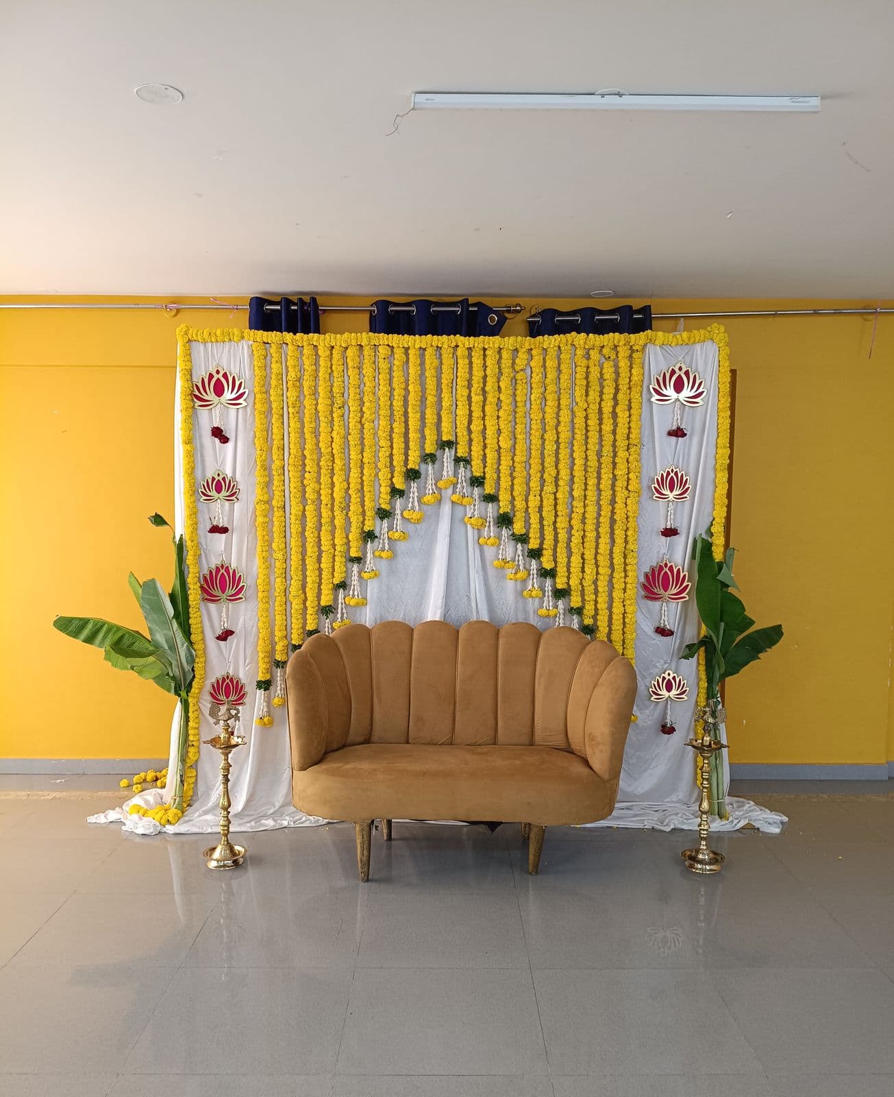 Haldi backdrop with marigold strings, white drapes and a gold chaise
