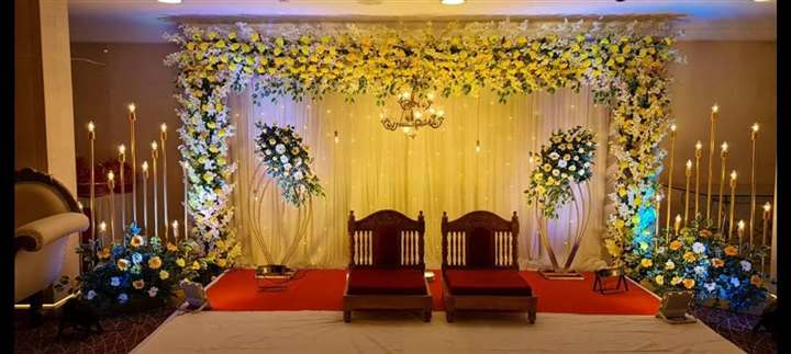 Banquet hall wedding stage with floral arch, yellow floral garlands and gold seating