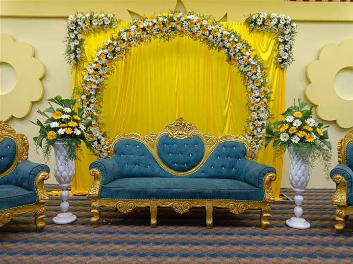 Gerbera daisy floral arch behind teal and gold seating for an engagement