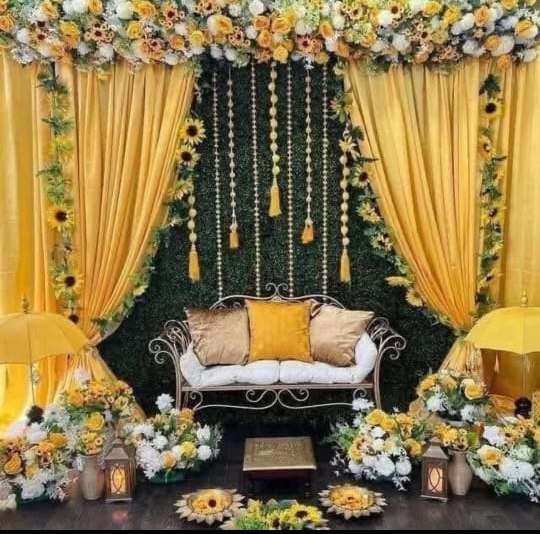 Sunflower and white floral haldi stage with hanging tassel strands on green wall