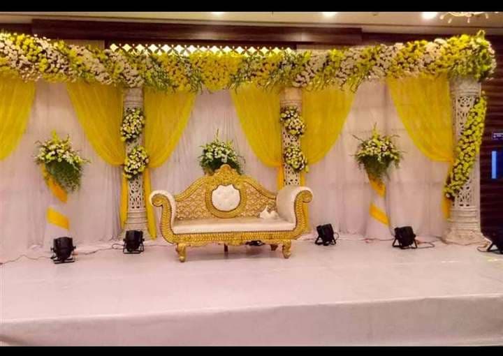 Nikah stage with carved pillars, yellow drapes and full floral canopy