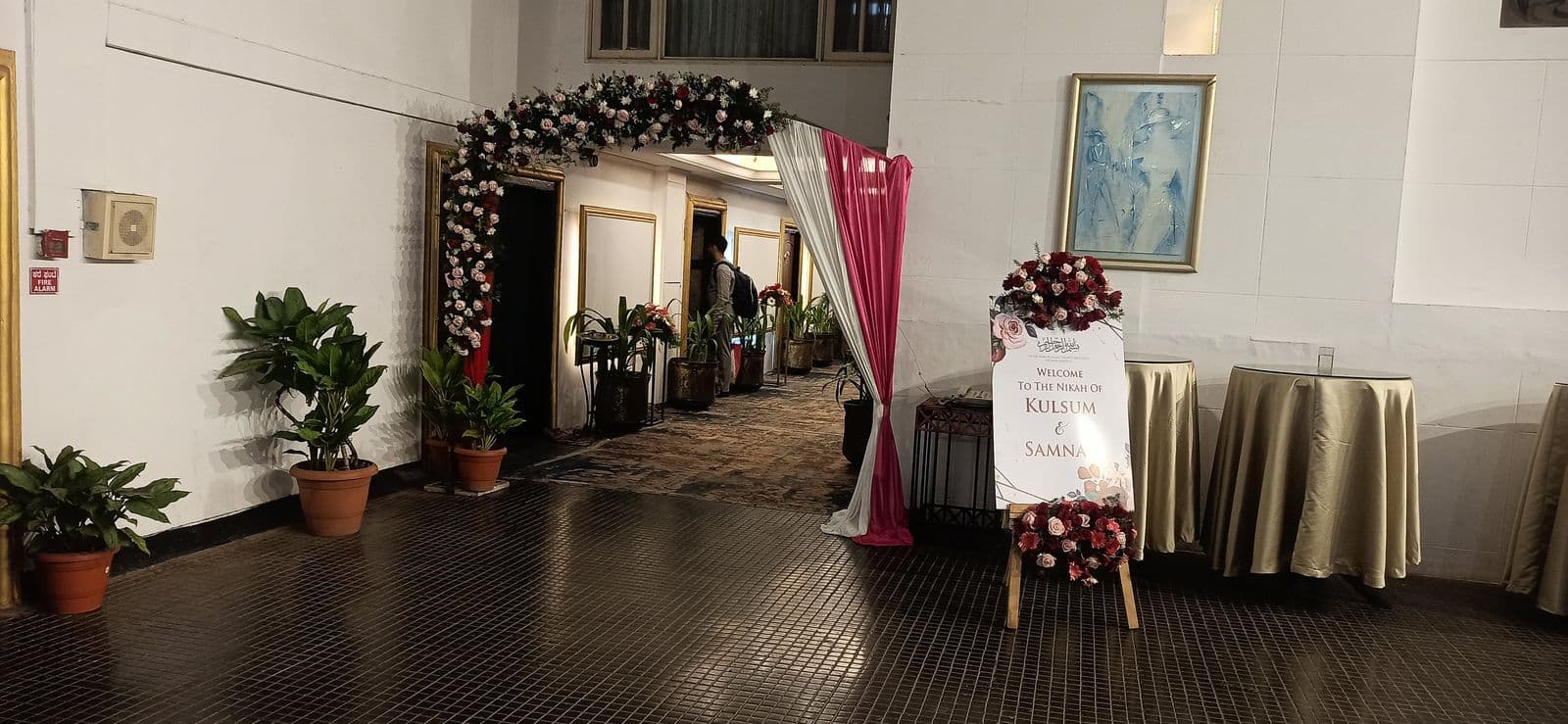 Floral arch at a banquet hallway entrance with welcome board