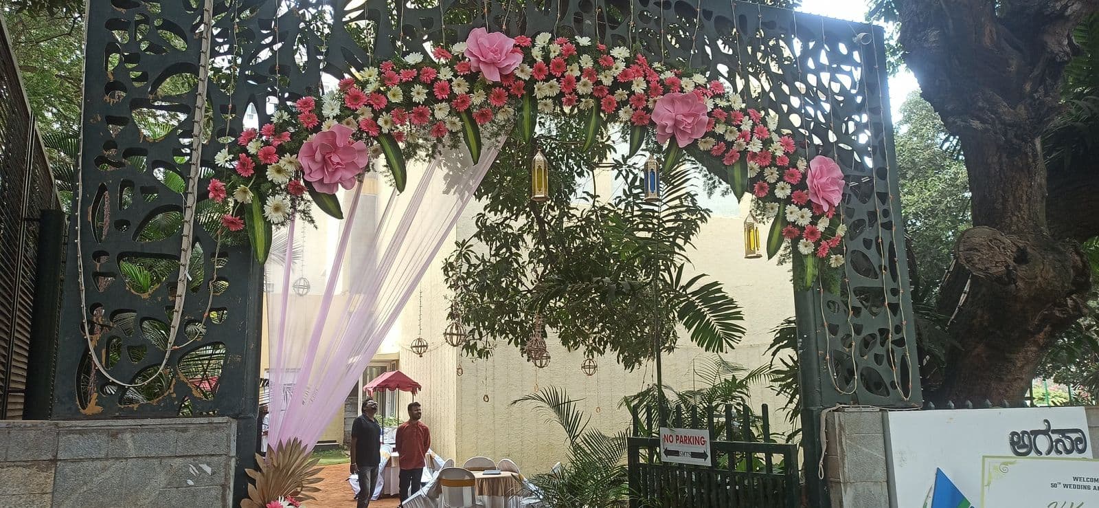 Outdoor gate framed with a pink and white floral arch