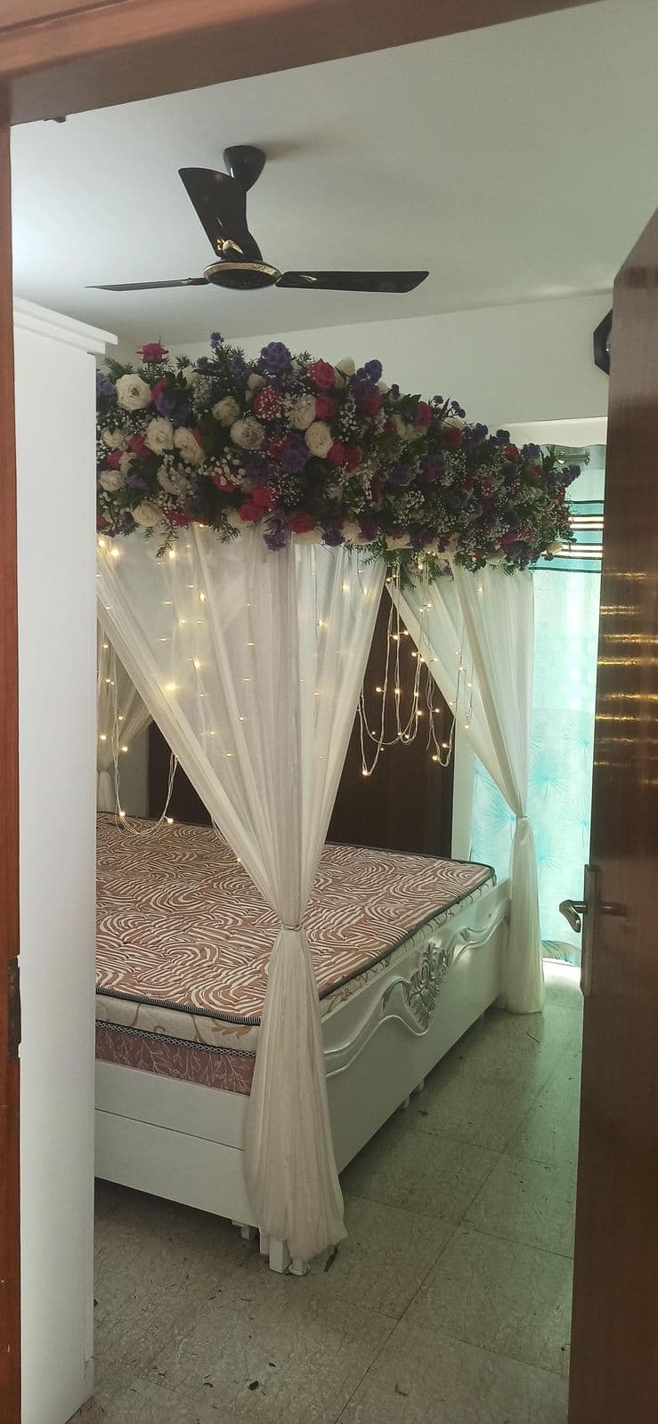 Bed canopy with white drapes and a rose crown
